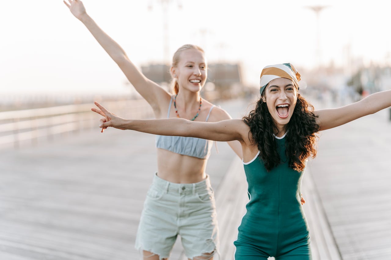 ours-journey Two young women joyful and carefree on a sunny boardwalk.